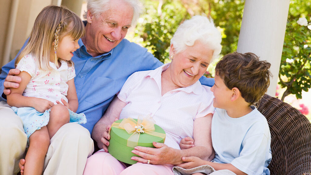Grandparents with grandchildren on patio with gift smiling