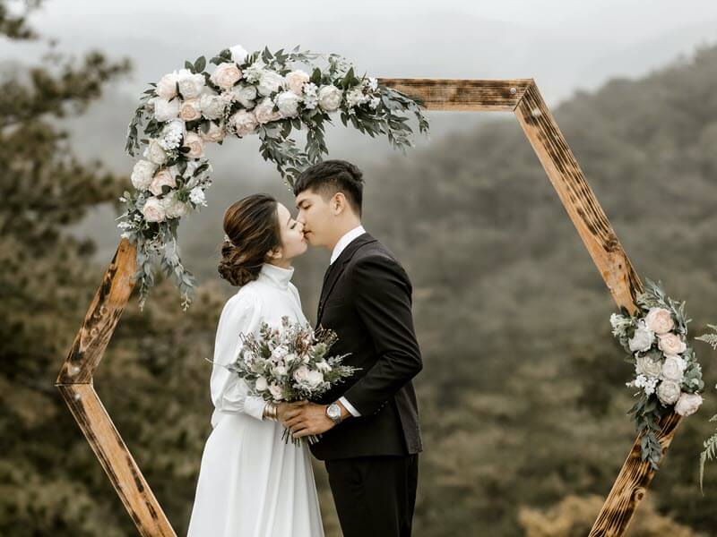 2023 wedding trends with couple kissing under flower arch