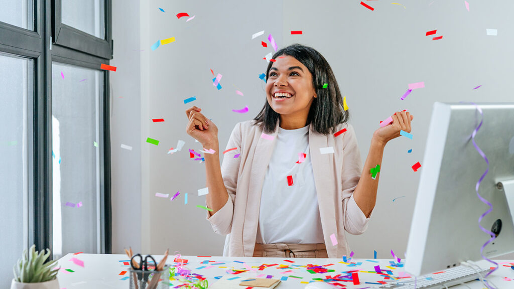 Young business woman having fun time catching confetti