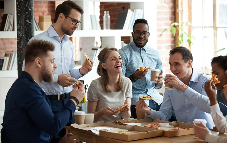 Happy diverse team people talking laughing eating pizza in office